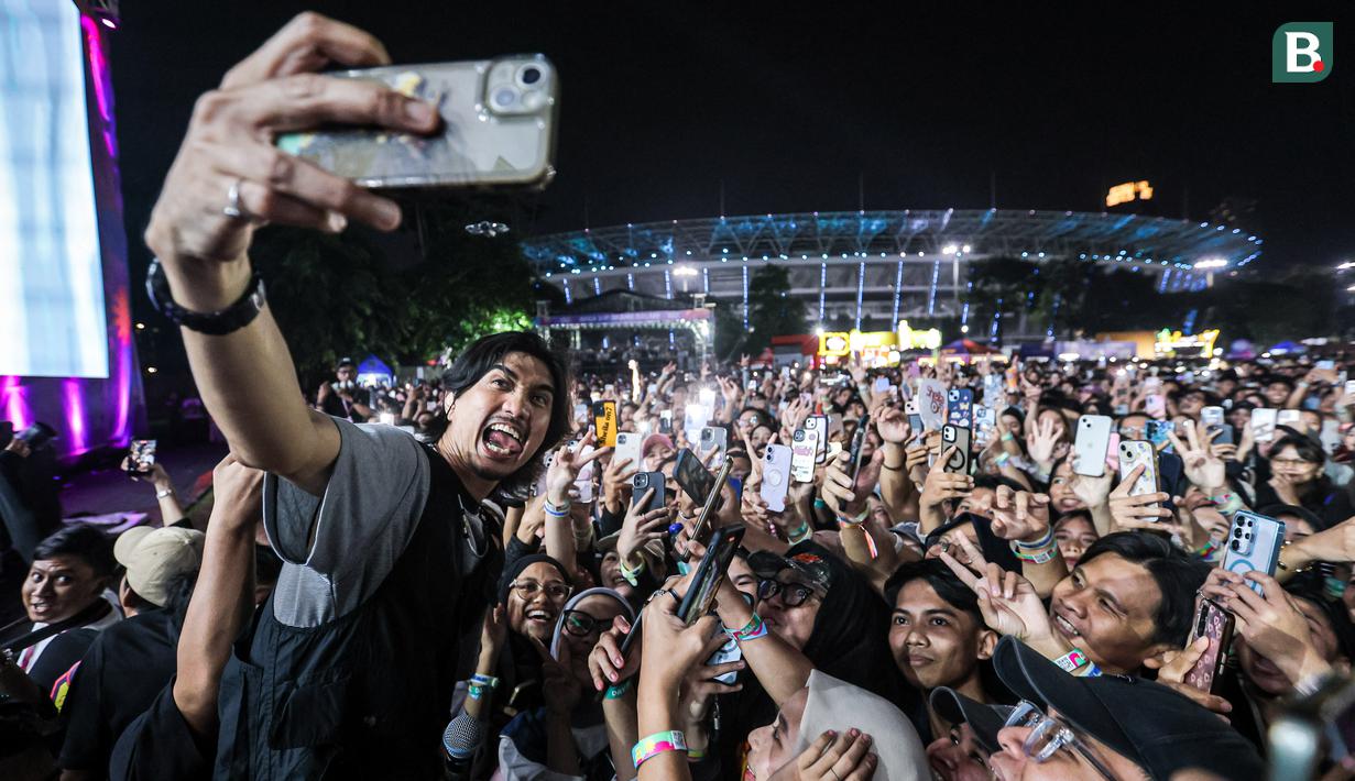 Vokalis Sheila on 7, Akhdiyat Duta Modjo melakukan swafoto bersama para penonton Kapanlagi Buka Bareng (KLBB) 2026 yang berlangsung di Stadion Madya, Senayan, Jakarta, Minggu (01/03/2026). (Bola.com/Bagaskara Lazuardi)