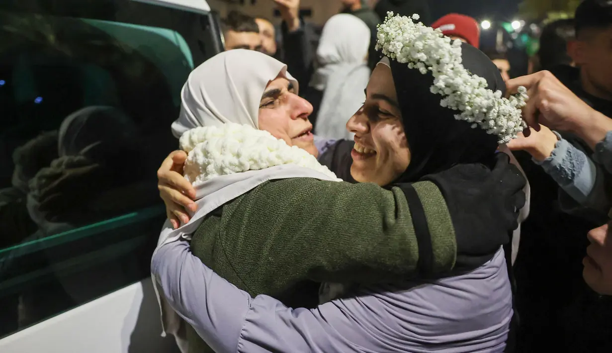Tahanan Palestina, Baraah Fuqaha (kanan) disambut oleh kerabatnya pada saat kedatangan pada dini hari tanggal 20 Januari 2025 di kota Tepi Barat yang diduduki, Beitunia, di pinggiran kota Ramallah. (Zain JAAFAR/AFP)