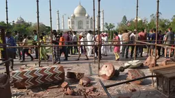 Wisatawan berkumpul di sekitar royal gate atau gerbang kerajaan setelah pilar Taj Mahal runtuh diterpa angin kencang di Agra, India, Kamis (12/4). Dua pilar Taj Mahal yang roboh diterpa angin kencang itu terdapat di gerbang masuk yang berbeda. (AFP Photo)