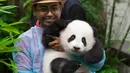 Seorang pekerja kebun binatang Malaysia memegang panda bayi ketika diperkenalkan kepada publik di Kuala Lumpur, Sabtu (26/5). Bayi panda yang lahir lima bulan lalu tersebut membuat penampilan media pertamanya. (AP Photo/Vincent Thian)