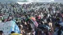 Orang-orang mendinginkan diri sambil bermain di sebuah pantai di Qingdao, China timur, pada 3 Agustus 2019. Banyak warga di Negeri Tirai Bambu memanfaatkan musim panas dengan mengunjungi pantai untuk mengisi liburan. (Photo by FRED DUFOUR / AFP)