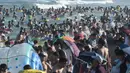 Orang-orang mendinginkan diri sambil bermain di sebuah pantai di Qingdao, China timur, pada 3 Agustus 2019. Banyak warga di Negeri Tirai Bambu memanfaatkan musim panas dengan mengunjungi pantai untuk mengisi liburan. (Photo by FRED DUFOUR / AFP)