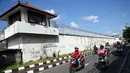 Pengendara sepeda motor melintas di samping bangunan Lembaga Pemasyarakatan (Lapas) Kerobokan, Bali, Senin (19/6). Empat narapidana asing kabur melalui lubang sepanjang 15 meter yang mengarah ke parit di luar bangunan Lapas. (SONNY TUMBELAKA/AFP)