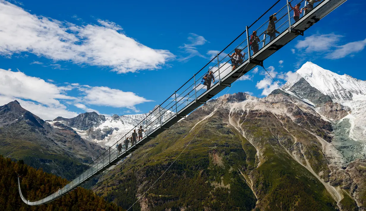 Wisatawan berjalan di atas jembatan gantung yang baru saja diresmikan di Kota Zermatt, Swiss, 29 Juli 2017. Jembatan sepanjang hampir 500 meter ini disebut-sebut sebagai jembatan gantung pejalan kaki terpanjang di dunia (Valentin Flauraud/Keystone via AP)