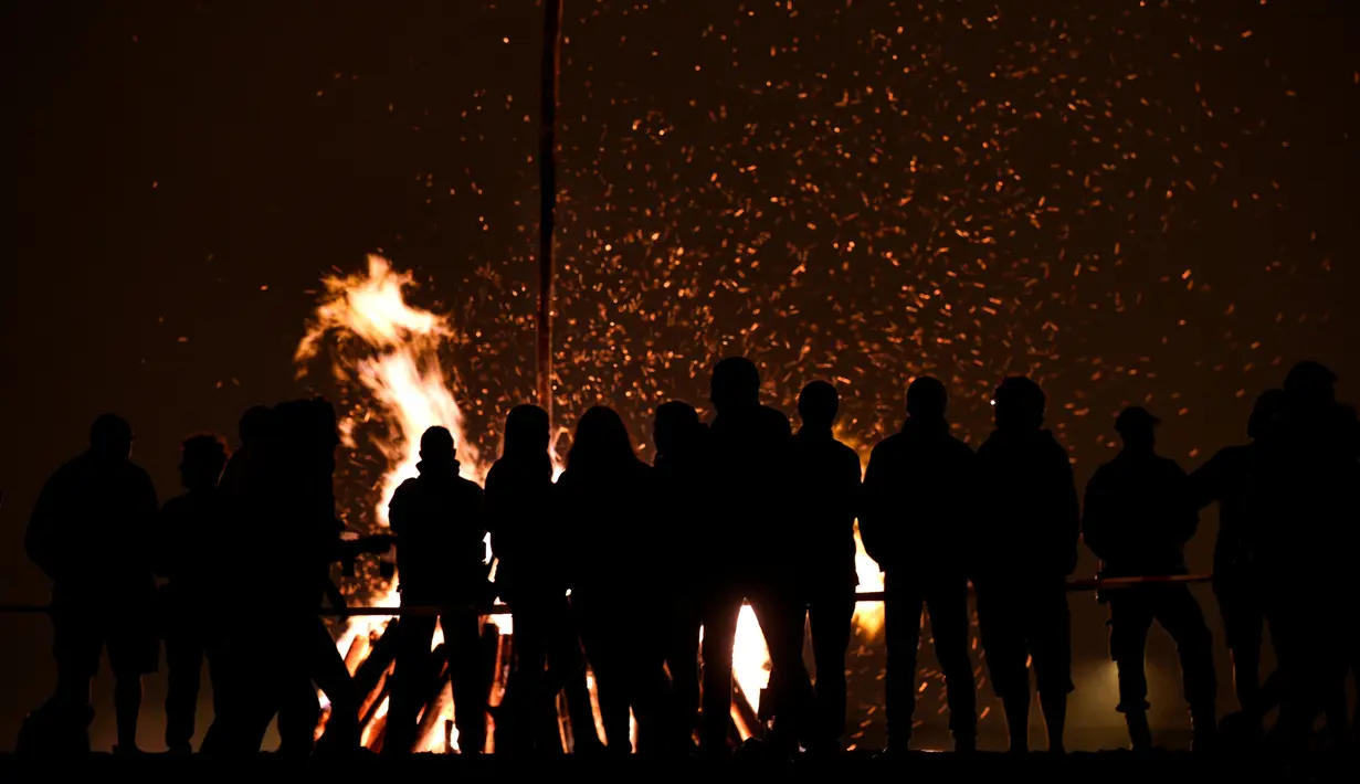 Sejumlah orang mengikuti tradisi malam San Juan's (Saint John) di Gijon, Spanyol, (24/6). Malam San Juan adalah upacara penyucian dimana warga membakar sejumlah benda yang sudah tidak diinginkan. (REUTERS/Eloy Alonso)