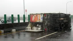 Sebuah truk terbalik di jalan saat topan super meranti disertai hujan dan angin kencang melanda Pingtung, Taiwan selatan, Rabu (14/9). Membawa angin kencang, hujan deras dan banjir, topan ini bergerak dengan kecepatan 216 kilometer per jam. (Sam YEH/AFP)
