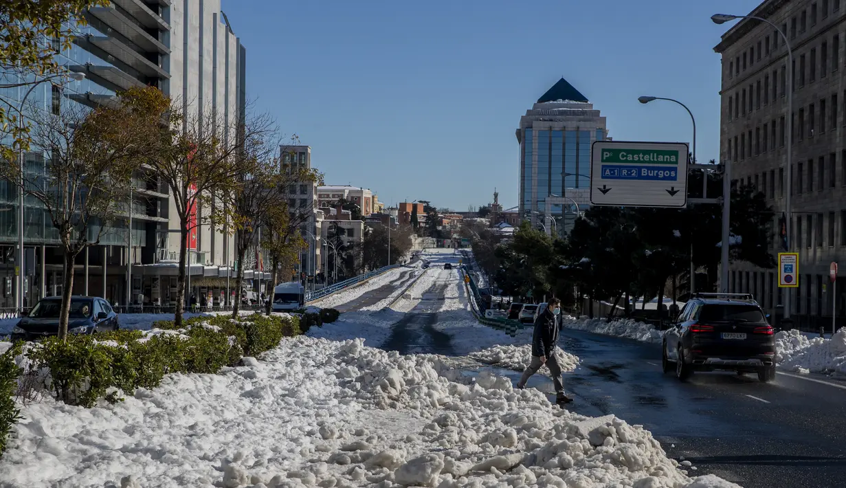 Seorang pria berjalan melewati salju di Madrid, Spanyol, Senin (11/1/2021). Ibu kota Spanyol itu berusaha bangkit kembali setelah menghadapi badai salju terburuk dalam 50 tahun terakhir yang melumpuhkan sebagian besar wilayah Spanyol tengah selama akhir pekan. (AP Photo/Manu Fernandez)