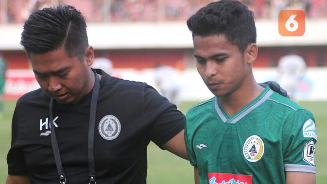 Pemain sayap PSS Sleman, Irkham Zahrul Mila (kanan) ditemani tim medis usai mengalami cedera saat melawan Madura United di Stadion Maguwoharjo, Minggu (29/9/2019). (Bola.com/Vincentius Atmaja)
