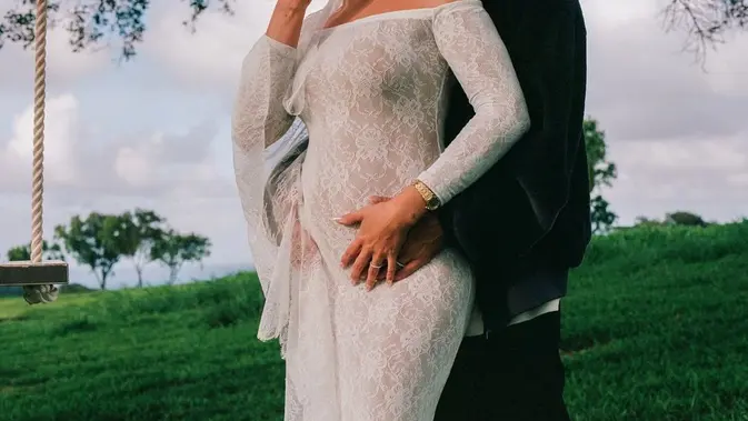 Hailey Bieber umumkan kehamilan dan pamer baby bump mengenakan gaun renda ala pengantin. [@justinbieber]