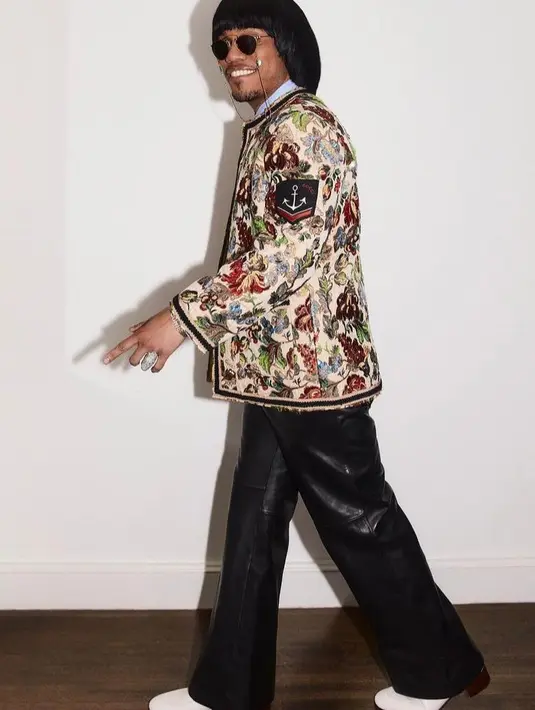 <p>Dia memadukan kemeja biru, celana kulit, dan dasi kulit yang dipadukan jaket bermotif floral. Gayanya disempurnakan dengan kacamata hitam.  (Instagram/anderson._.paak).</p>