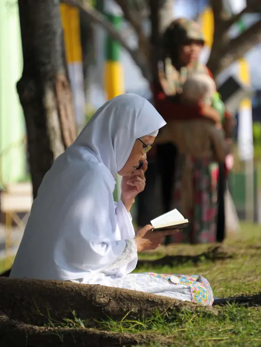 Warga Aceh berdoa di pemakaman massal Ulhee Lheue, Banda Aceh, Sabtu (26/12/2015).  Doa tersebut untuk keluarga mereka yang terkena bencana Tsunami pada 26 Desember 2014. (AFP Photo/ Chaideer Mahyuddin)