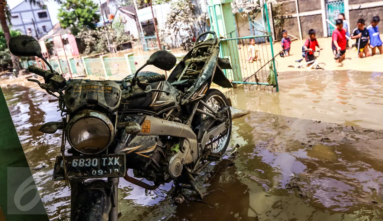 Sebuah motor dilumuri air lumpur terlihat dibiarkan saja oleh pemiliknya di halaman masjid komplek Pondok Gede Permai, Bekasi, Jumat (22/4). Sejak banjir menerjang perumahan tersebut hanya sekitar 50 warga yang mau dievakuasi. (Liputan6.com/Fery Pradolo)