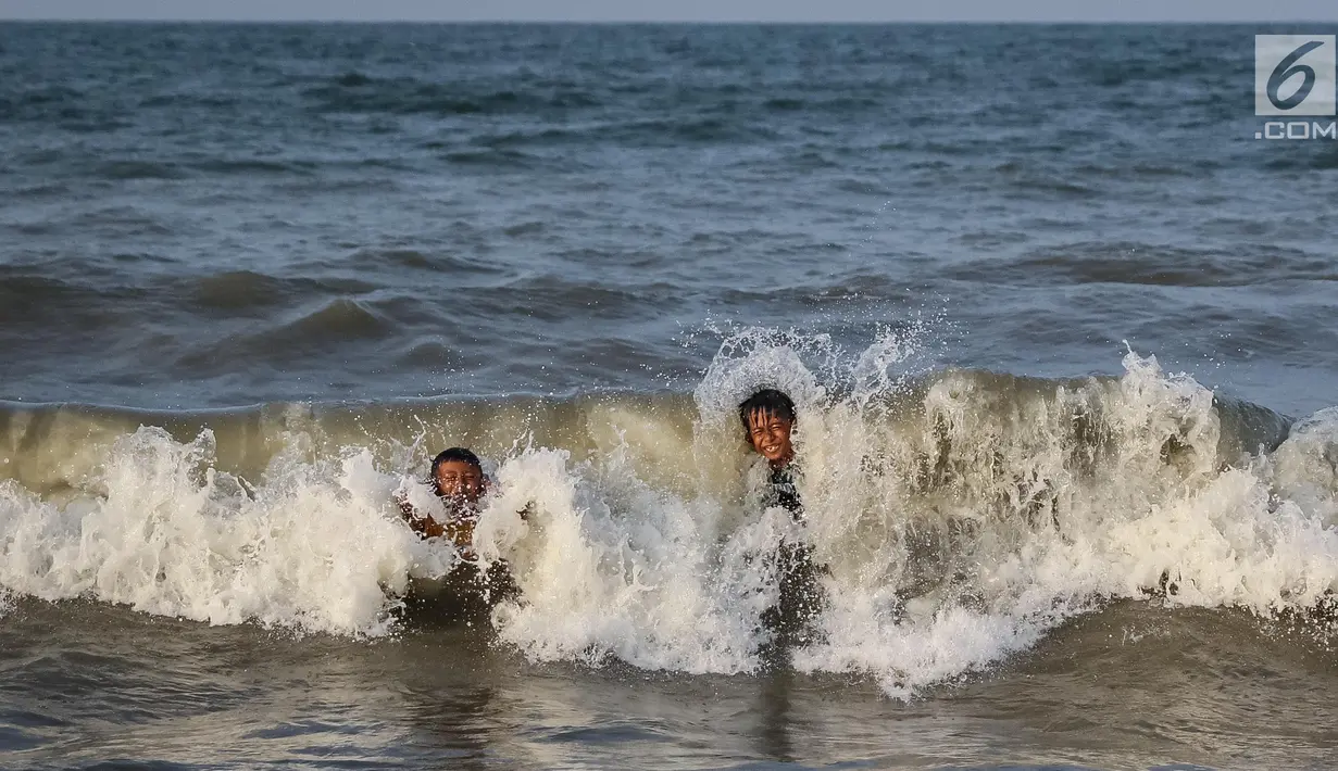 Dua orang bocah bermain ombak di Pantai Randusanga Indah, Brebes, Jawa Tengah, Minggu (2/7). Pantai Randusanga Indah menjadi salah satu destinasi wisata bagi para pemudik yang melewati jalur Pantura. (Liputan6.com/Faizal Fanani)