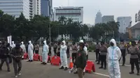 Aksi demonstrasi driver ojek online (ojol) di kawasan Patung Kuda Jakarta, dikawal sejumlah anggota polisi yang menggunakan baju hazmat.