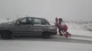 Petugas membantu mendorong kendaraan yang terjebak di salju di Provinsi Hormozgan di selatan Iran (4/1/2022). Sedikitnya dua orang tewas dalam banjir bandang di provinsi selatan Iran, Fars, kata seorang pejabat setempat. (AFP/Iranian Red Crescent)