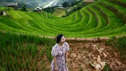 Seorang perempuan berfoto dengan latar belakang sawah terasering di distrik Mu Cang Chai, Vietnam pada 18 September 2020. Pesawahan terasering di Mu Cang Chai merupakan destinasi-destinasi wisata yang atraktif dan menyerap kedatangan banyak wisatawan domestik dan mancanegara. (Manan VATSYAYANA/AFP)