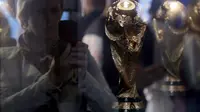 A woman is seen through the glass while taking pictures of the World Cup trophy, which is on display during a ceremony marking 1,000 days until the beginning of the 2018 FIFA World Cup in central Moscow, Russia, September 18, 2015. REUTERS/Maxim Shemetov