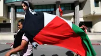 Orang-orang melambaikan bendera Palestina selama protes untuk mengekspresikan solidaritas mereka terhadap Gaza di ibu kota Tunisia, Tunis, pada 21 Oktober 2023, di tengah pertempuran yang sedang berlangsung antara Israel dan kelompok Palestina Hamas. (FETHI BELAID / AFP)