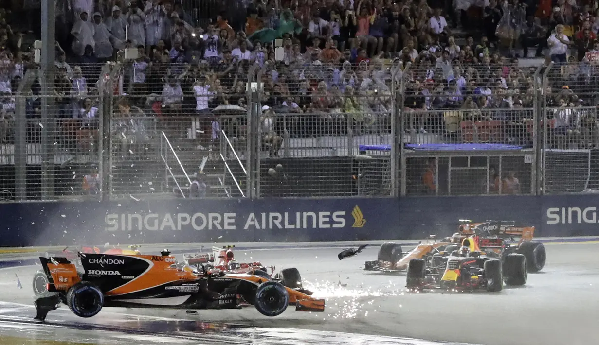 Mobil pebalap McLaren, Fernando Alonso (kiri) terpental saat bertabrakan dengan pebalap Ferrari, Kimi Raikkonen pada balapan F1 GP Singapura di Marina Bay City Circuit (17/9/2017). Duo pebalap Ferrari gagal melanjutkan balapan.  (AP/Wong Maye-E)