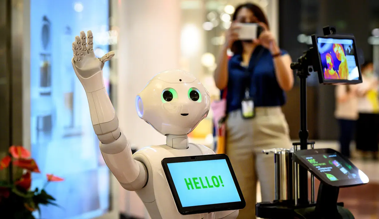Seorang perempuan mengambil gambar robot 5G yang menyambut pengunjung di pusat perbelanjaan di Bangkok, Thailand, Kamis (4/6/2020). Thailand menggunakan teknologi di garis depan untuk menjaga ruang publik dari penyebaran pandemi corona Covid-19. (Mladen ANTONOV / AFP)