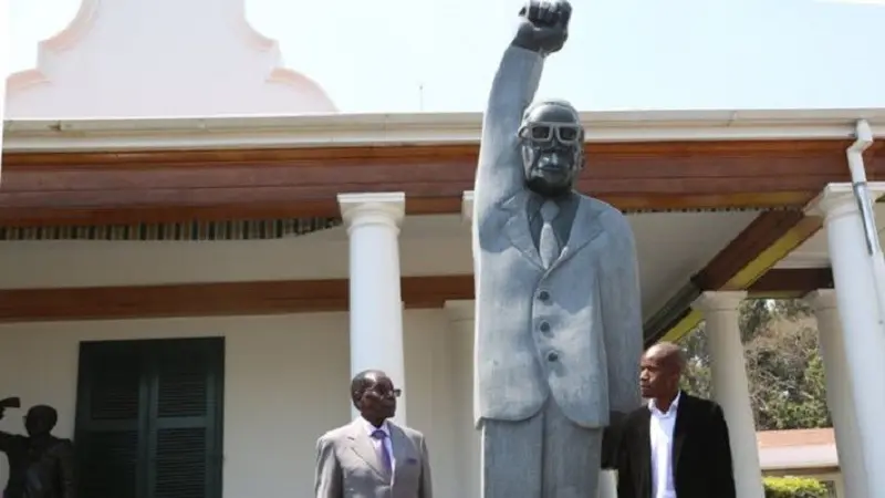 Presiden Zimbabwe Robert Mugabe (berjas abu-abu) berpose dengan patung dirinya 