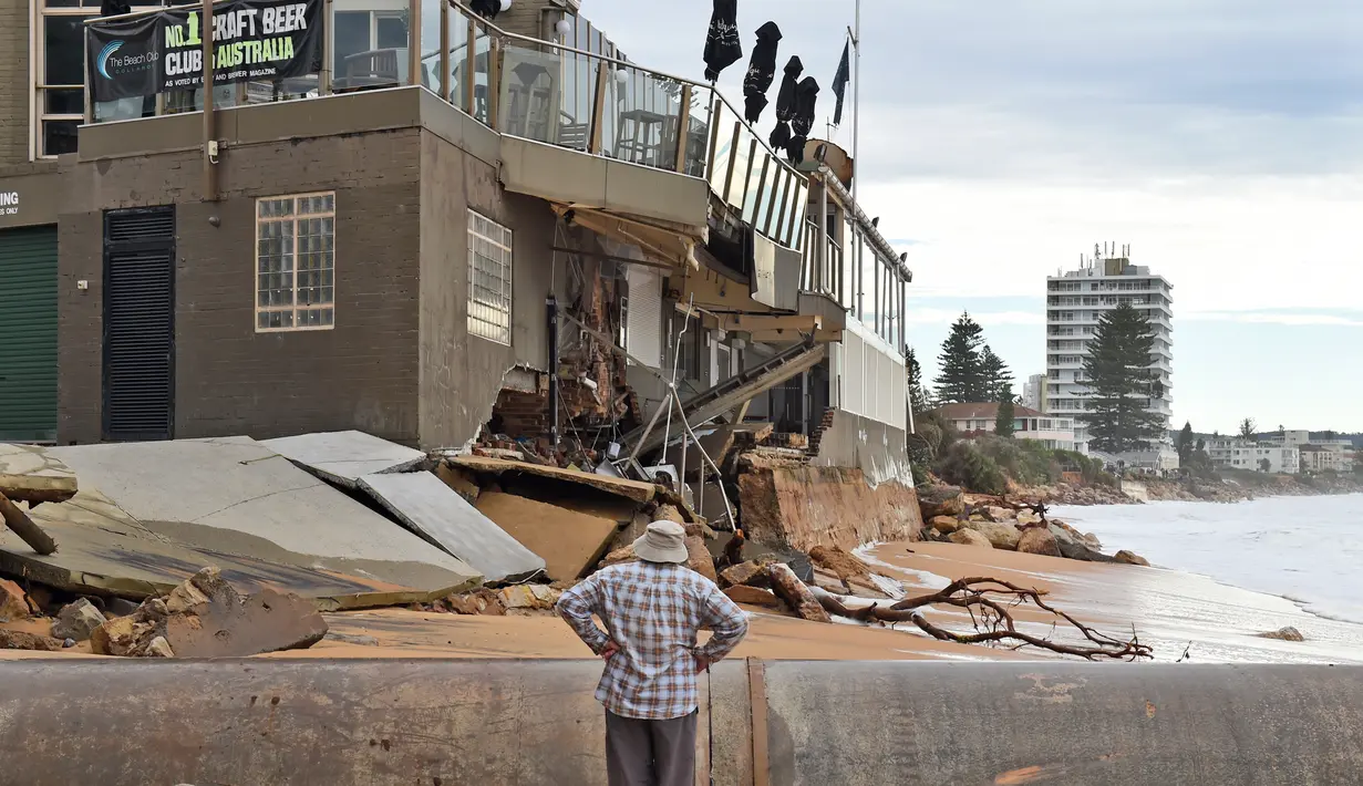 Seorang warga melihat bangunan yang rusak akibat badai yang melanda Pantai Utara Sydney (6/6/2016). Tiga orang dikabarkan tewas akibat cuaca buruk tersebut. (AFP Photo/William West)