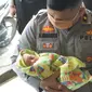 Kapolsek Tampan Kompol Hotmartua Ambarita menggendong bayi yang dibuang orangtuanya di salah satu panti asuhan di Pekanbaru. (Liputan6.com/M Syukur)