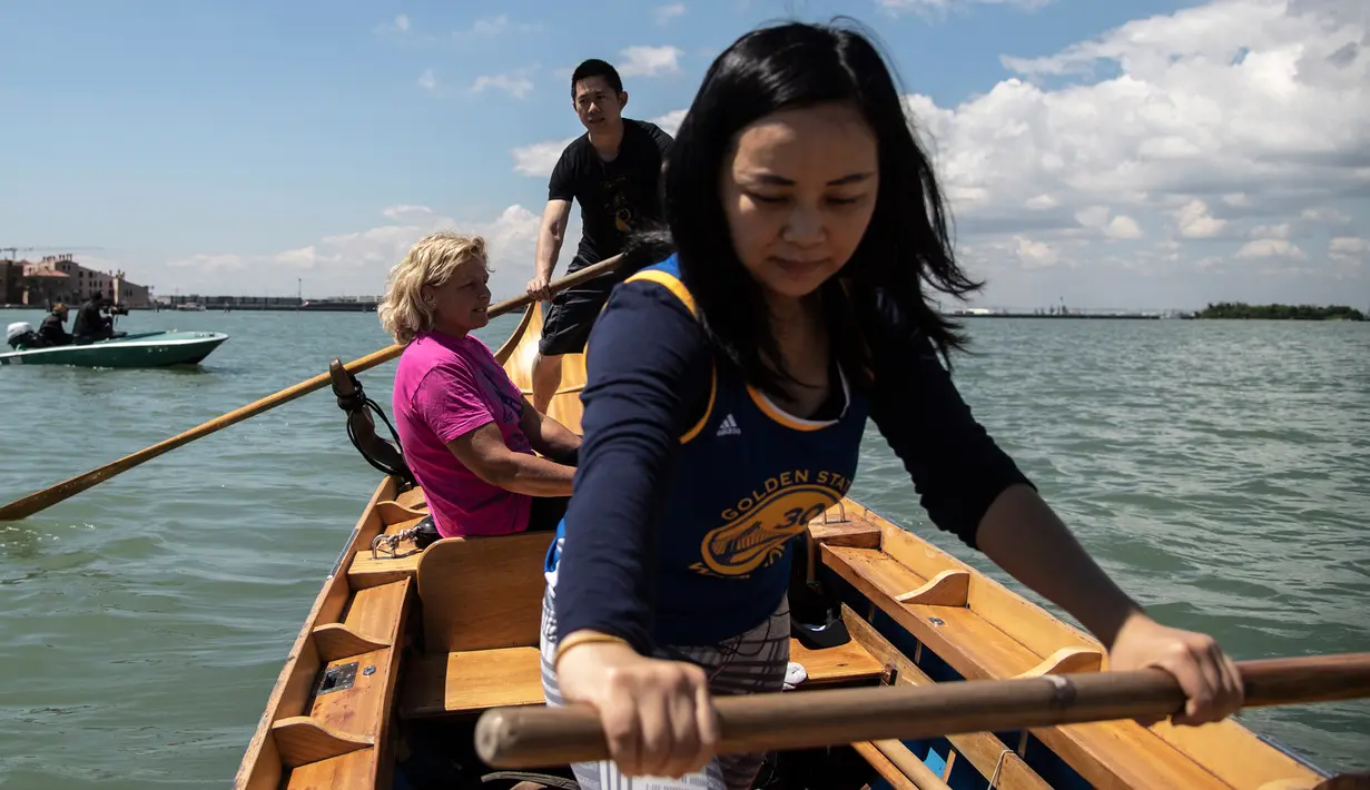 Gabriella Lazzari, anggota Row Venice, mengajarkan mendayung gondola bagi wisatawan di sebuah kanal di Venesia, Italia pada 16 Mei 2019. Pengalaman ini bisa dimiliki dengan sekitar Rp 1,37 juta per gondola selama 90 menit untuk empat orang yang dimulai pukul 10.00 pagi. (MARCO BERTORELLO/AFP)