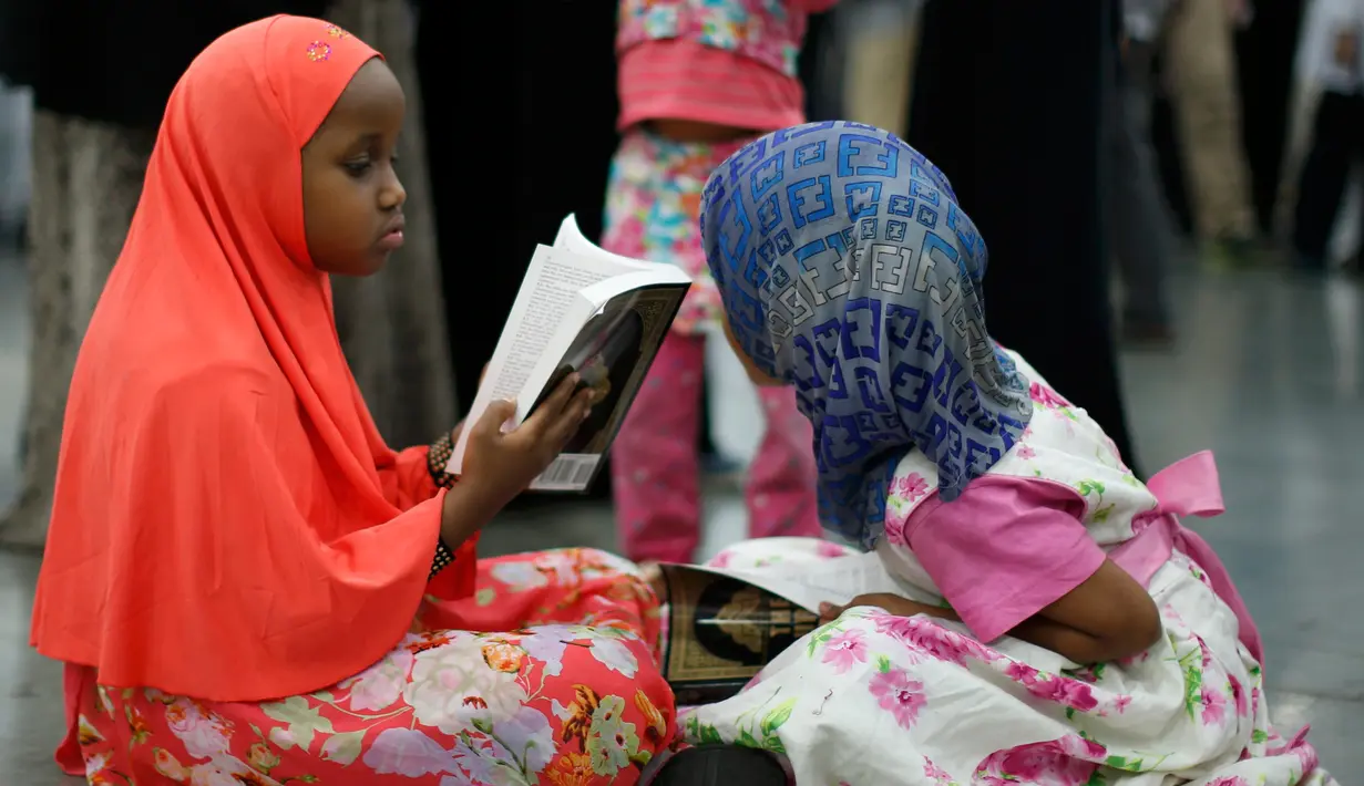 Seorang anak membaca Al Quran ketika menghadiri salat jenazah Muhammad Ali di Louisville, Kentucky, AS, Kamis (9/6). Suasana khusyuk terlihat selama prosesi penghormatan terakhir jelang pemakaman legenda tinju dunia, Muhammad Ali. (REUTERS/Lucy Nicholson)