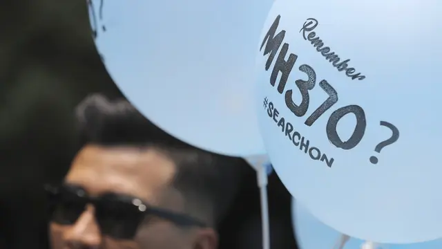 Seorang relawan membagikan balon bergambar MH370 pada acara Day of Remembrance MH370 di Kuala Lumpur, Malaysia, Minggu, 3 Maret 2019. (Foto AP/Vincent Thian)
