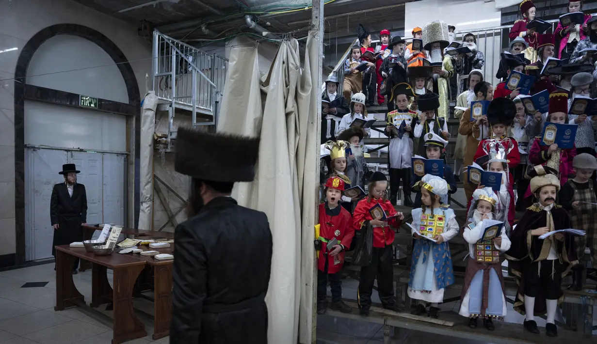 Pria dan anak-anak Yahudi ultra-Ortodoks, beberapa mengenakan kostum saat merayakan festival Yahudi Purim di sebuah sinagoga di Bnei Brak, Israel, Senin (6/3/2023). Hari raya Purim Yahudi memperingati keselamatan orang Yahudi dari genosida di Persia kuno, sebagaimana diceritakan dalam Kitab Ester. (AP Photo/Oded Balilty)