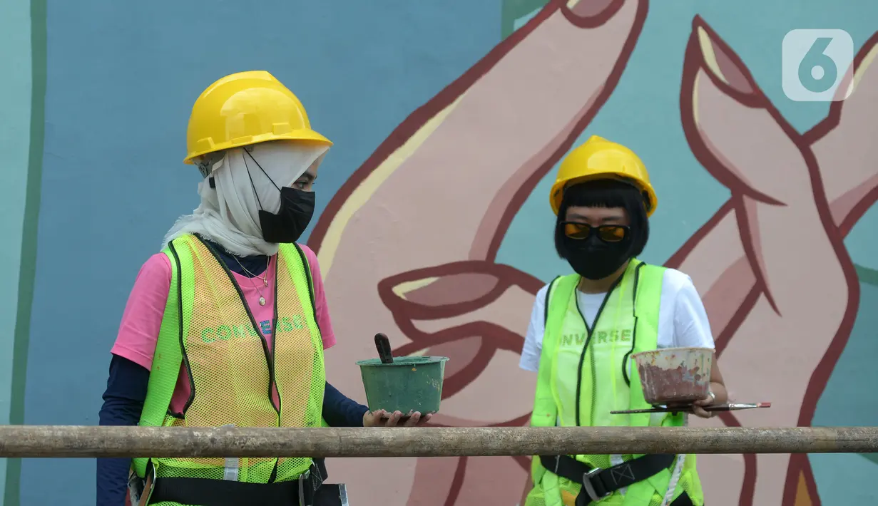 Dua muralis perempuan menyelesaikan pembuatan mural pada dinding di kawasan Juanda, Jakarta, Rabu (16/6/2021). Mural tersebut berjudul "Setara Berkarya untuk Ibu Pertiwi". (merdeka.com/Imam Buhori)