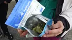 Seorang pria menunjukkan dua kemasan ganja yang baru dibeli di apotek di Montevideo, Uruguay (19/7). Urugay menjadi yang pertama di dunia yang secara resmi melegalkan produksi dan penjualan ganja. (AFP Photo/Miguel Rojo)