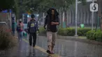 Warga menutupi kepala dari guyuran hujan saat melintasi kawasan Sudirman, Jakarta, Kamis (4/1/2024). (Liputan6.com/Angga Yuniar)