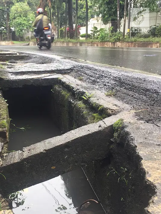 Pengendara melintas di samping selokan tanpa penutup di Jalan Mohammad Kahfi I, Jagakarsa, Jakarta, Selasa (22/1). Selain membahayakan pejalan kaki, kondisi tersebut juga berbahaya bagi pengendara terutama saat malam hari. (Liputan6.com/Immanuel Antonius)
