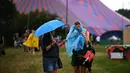 Pengunjung festival berlindung dari hujan pada hari pertama festival Glastonbury di desa Pilton, di Somerset, Inggris barat daya, pada 21 Juni 2023. (Photo by Oli SCARFF / AFP)
