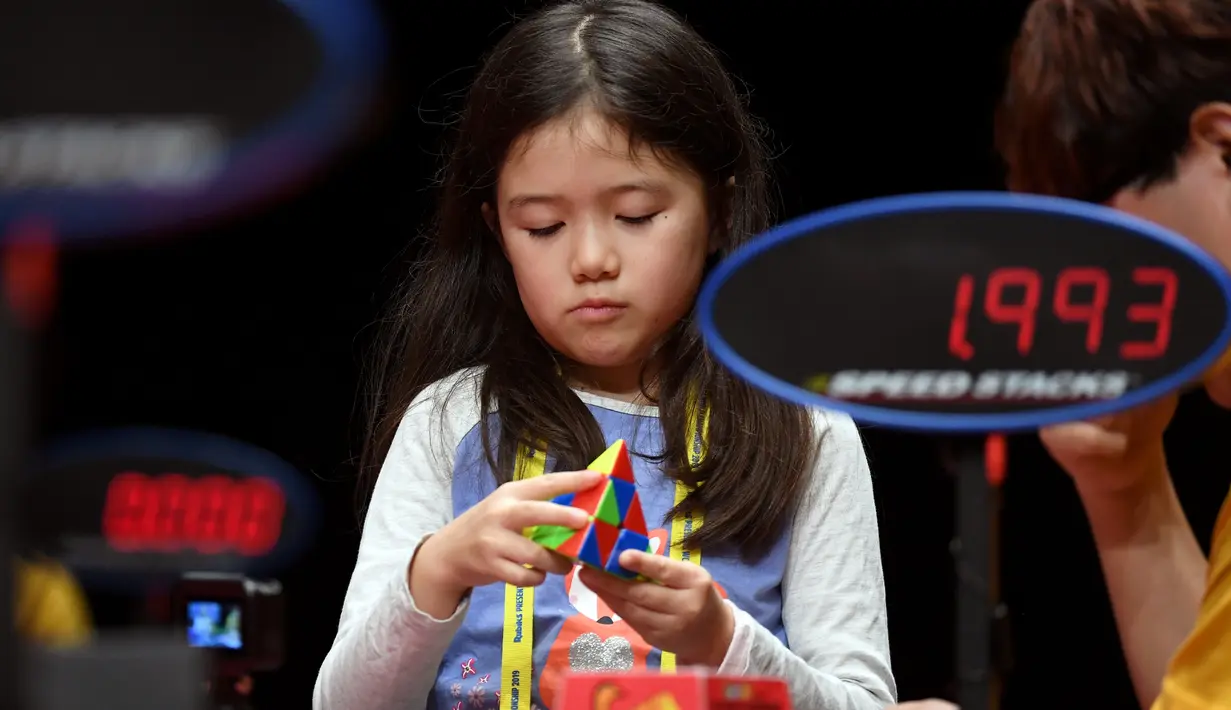 Seorang anak perempuan serius memecahkan permainan rubik pada kejuaraan kubus Rubik Dunia di Melbourne, Australia (12/7/2019). Kejuaraan Dunia diadakan setiap dua tahun dan telah menarik 905 pesaing dari seluruh dunia yang bersaing dalam 18 acara yang berbeda. (AFP Photo/William West)