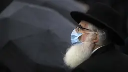 Rabbi Rafael Schaffer mengenakan masker untuk perlindungan terhadap infeksi COVID-19 saat Hari Peringatan Holocaust Nasional di Bucharest, Rumania, Jumat (9/10/2020). Pada tahun 1941, orang Yahudi dan Roma dideportasi dari Rumania saat negara itu diperintah rezim pro Nazi. (AP Photo/Vadim Ghirda)