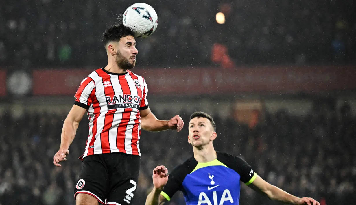 Bek Sheffield United George Baldock (Kiri) menyundul bola di sebelah gelandang Tottenham Hotspur Ivan Perisic  pada putaran kelima Piala FA 2022/2023 di Bramall Lane, Rabu (2/3/2023) dini hari WIB. Tottenham Hotspur tersingkir dari Piala FA setelah kalah dari Sheffield United dengan skor 0-1. (Photo by Oli SCARFF / AFP)