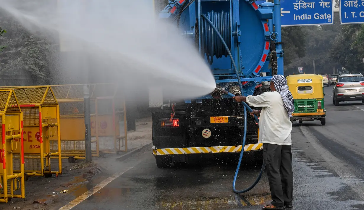 Petugas menyemprotkan air ke pohon-pohon di pinggir jalan New Delhi, India, Rabu (6/11/2019). Hal tersebut dilakukan dalam upaya untuk mengurangi polusi udara dengan memerangi akumulasi debu. (Photo by Prakash SINGH / AFP)