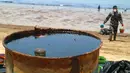 Petugas membersihkan Pantai Benua Patra setelah tumpahan minyak di sekitarnya, Balikpapan, Kalimantan Timur, Senin (2/4). Pembersihan pantai dilakukan secara manual agar lebih efektif untuk mengumpulkan ceceran minyak. (AFP)