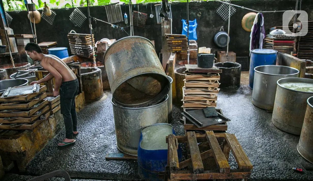 Pekerja merapikan tatakan di pabrik tahu tempe yang berhenti operasi di kawasan Duren Tiga, Jakarta, Sabtu (2/12/2021). Puskopti mengimbau kepada seluruh anggota untuk menaikkan harga jual tahu dan tempe minimal 20 persen dari harga awal untuk mengantisipasi kerugian. (Liputan6.com/Faizal Fanani)