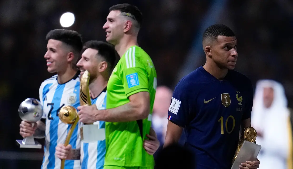Pemain Prancis Kylian Mbappe (kanan) membawa penghargaan Sepatu Emas saat pemain Argentina Enzo Fernandez (kiri), Lionel Messi, dan penjaga gawang Emiliano Martinez memegang penghargaan mereka setelah Argentina mengalahkan Prancis pada pertandingan sepak bola final Piala Dunia 2022 di Lusail Stadion, Lusail, Qatar, 18 Desember 2022. Argentina menang 4-2 dalam adu penalti melawan Prancis setelah pertandingan berakhir imbang 3 -3. (AP Photo/Natacha Pisarenko)