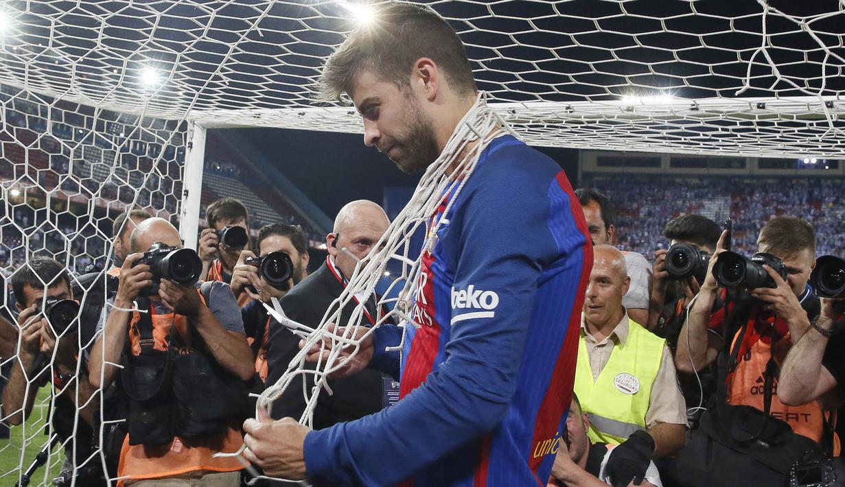 Bek Barcelona, Gerard Pique, memotong jaring gawang usai mengalahkan Alaves pada laga final Copa Del Rey di Stadion Vicente Calderon, Madrid, Sabtu (27/5/2017). Barcelona menang 3-1 atas Alaves. (EPA/Mariscal)