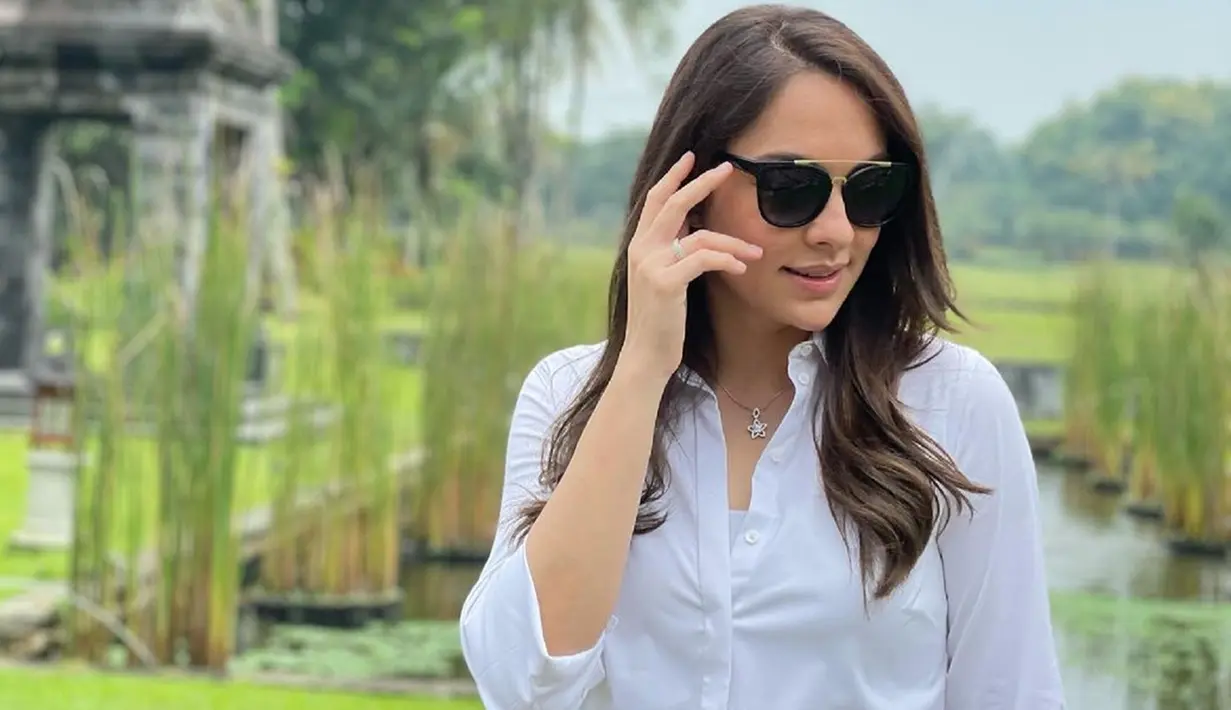 Tampil dengan busana berwarna putih, Reisa Broto Asmoro terlihat melengkapi penampilannya menggunakan kacamata hitam. Makeup natural dan rambutnya dibiarkan terurai, pesonanya kian terpancar.(Liputan6.com/IG/@reisabrotoasmoro)