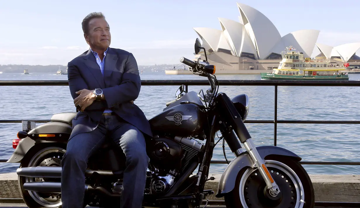Arnold Schwarzenegger berpose di atas motor Harley Davidson di depan Sydney Opera House, Australia, Kamis (4/6/2015). Aktor AS berusia 67 mengunjungi Sydney untuk menghadiri pemutaran perdana film terbaru 'Terminator Genisys'. (REUTERS/David Gray)