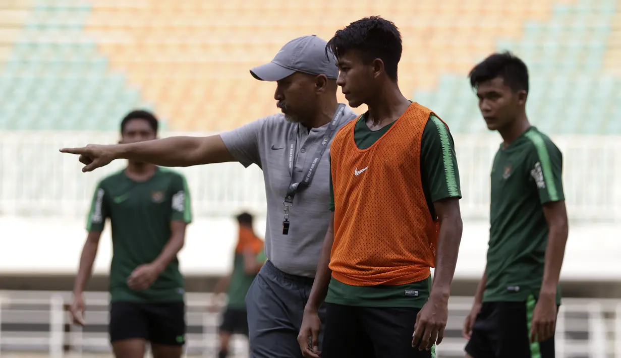 Pelatih Timnas Indonesia U-19, Fakhri Husaini, memberikan arahan kepada Mochammad Supriadi saat latihan di Stadion Pakansari, Bogor, Rabu (2/10). Latihan ini merupakan persiapan jelang AFF U-19 di Vietnam. (Bola.com/Yoppy Renato)