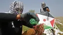 Warga Palestina menyiapkan bom molotov untuk diterbangkan menggunakan layang-layang di atas pagar perbatasan dengan Israel, di pinggiran timur Kota Gaza (20/4). Unjuk rasa warga Palestina terhadap Isrel memasuki minggu keempat. (AFP Photo/Mohammed Abed)