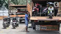 Petugas menaikkan sepeda motor milik peserta mudik gratis ke atas truk di Terminal Pulo Gadung, Jakarta, Selasa (26/4/2022). Pemprov DKI Jakarta mengadakan mudik gratis bagi warga yang memiliki KTP domisili DKI Jakarta dan telah vaksin COVID-19 booster. (merdeka.com/Iqbal S. Nugroho)