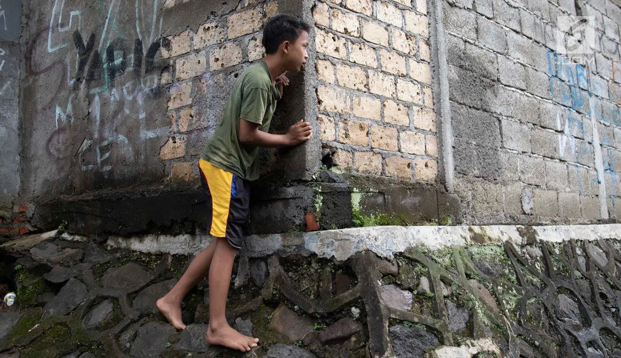 Seorang anak mengintip proses evakuasi KRL yang anjlok di kawasan Kebon Pedes, Bogor, Jawa Barat, Minggu (10/3). Kepala Daop I Jakarta Dadan Risdiansyah memastikan penanganan KRL yang anjlok selesai hari ini. (Liputan6.com/Immanuel Antonius)